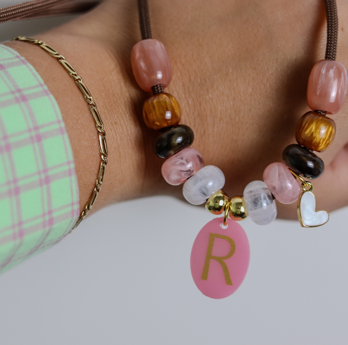 Deze handgemaakte hondenketting 'Rosé glow' is opgebouwd uit een stevig bruin koord met een stijlvolle mix van kralen. Het ontwerp combineert glanzende warmroze, zachtroze en marmerwitte kralen met diepbruine en goudkleurige accenten voor een luxe uitstraling.
