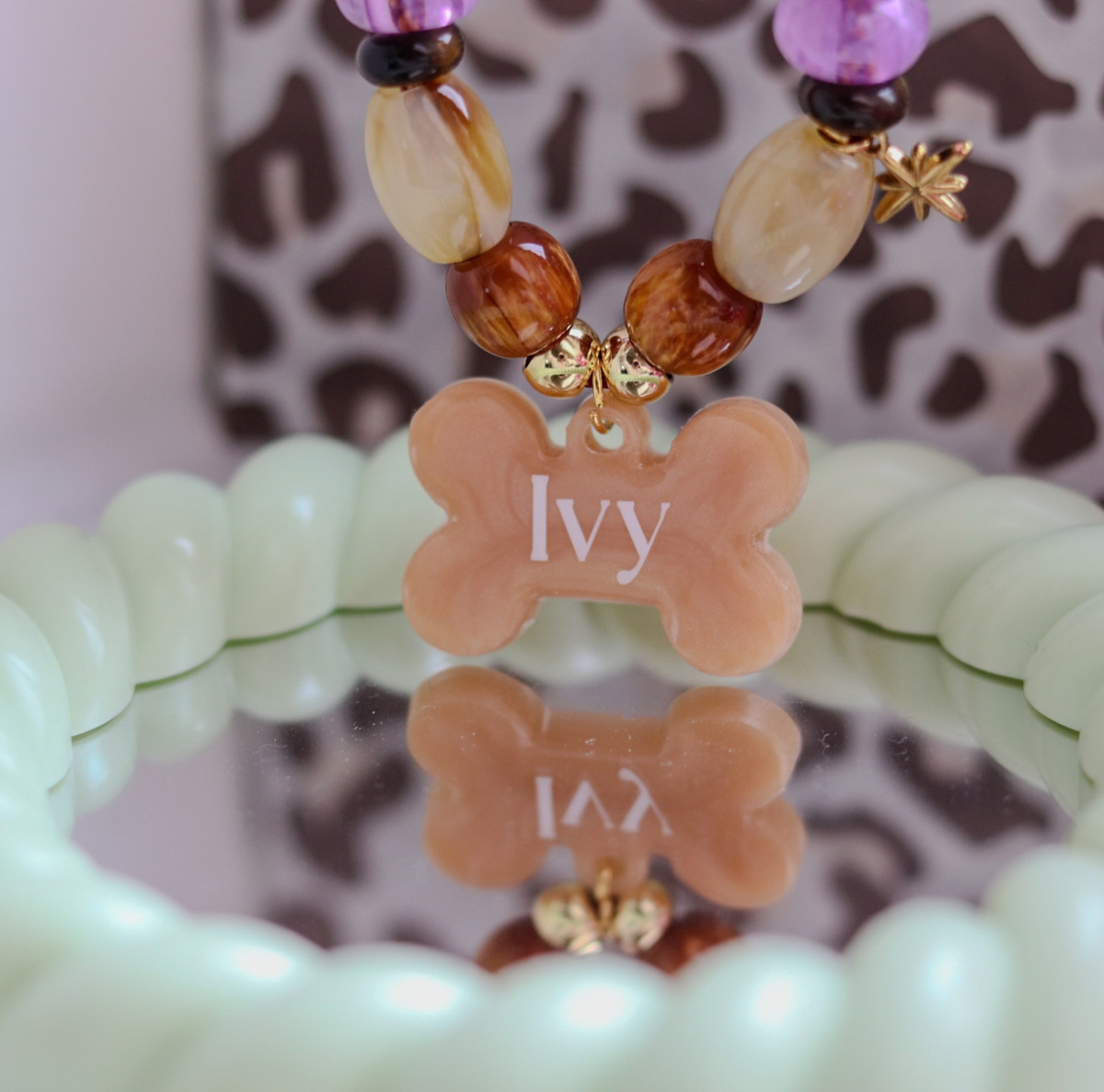 Handgemaakte hondenketting aan een roestbruin koord met amberkleurige en beige kralen, een glinsterend sterretje en een personaliseerbare botvormige naamhanger.
